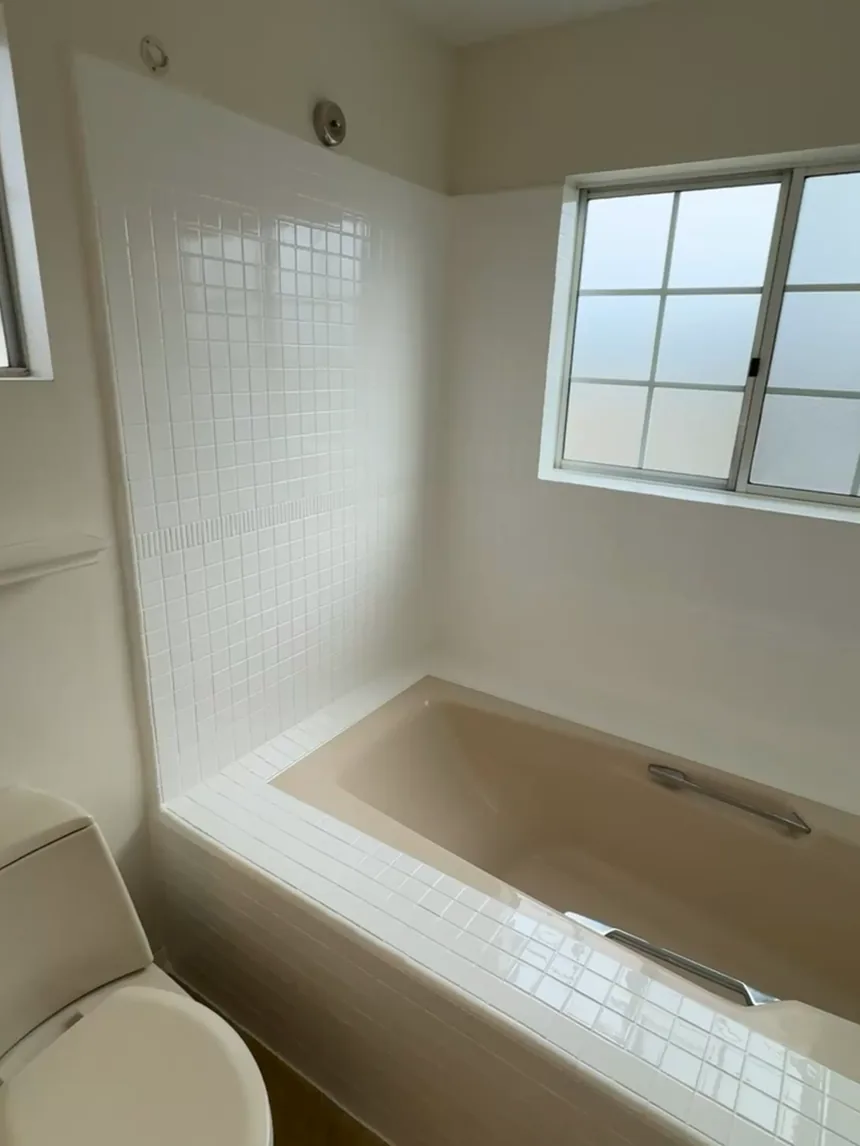 A bathroom with the tub surround and deck tile refinished in white.